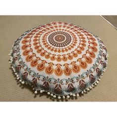 an orange and white round pillow with pom poms on the bottom of it