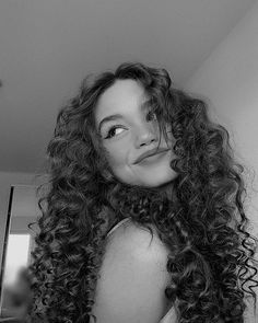 a woman with long curly hair is posing for the camera in black and white photo