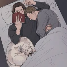 a man and woman laying in bed next to a dog with a book on their lap