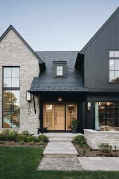 a house with black shingles and stone steps leading up to the front door area