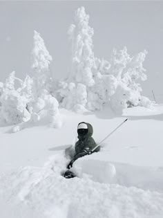 a man riding skis down the side of a snow covered slope next to trees