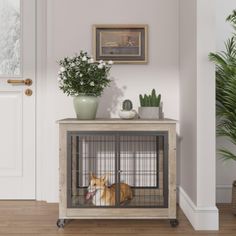 a dog is sitting in its cage on the floor next to a potted plant