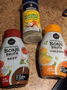 three bottles of broth and seasoning on a counter