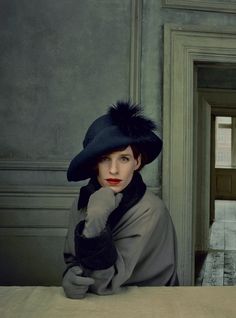 a woman sitting at a table wearing a black hat