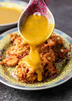 a person pouring sauce on some fried food