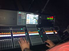 a person sitting in front of a sound mixing desk with many different colored buttons on it