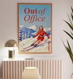 a poster on the wall above a table with a lamp and chair next to it