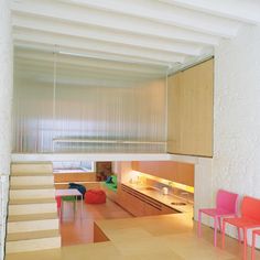 an open living room with stairs leading up to the kitchen and dining area, as well as colorful chairs