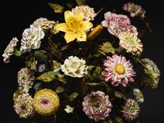 a vase filled with lots of colorful flowers on top of a table next to a black wall