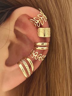 a close up of a person wearing gold ear cuffs with leaves on the top and bottom