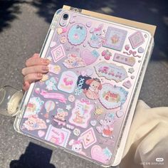 a person holding up a clear case with stickers on it's side and in front of her