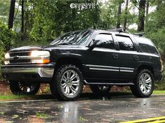 a black suv is parked in the rain