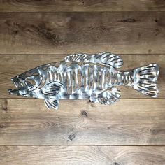 a metal fish sitting on top of a wooden floor next to a wood plank wall