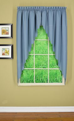 an open window with green grass in the middle and blue curtains hanging on the side