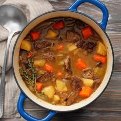 a pot filled with stew and carrots on top of a wooden table