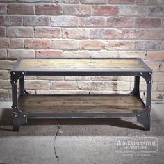 a wooden and metal coffee table against a brick wall