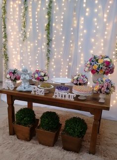 a wooden table topped with potted plants next to a wall covered in fairy lights