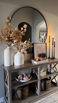 a table with candles, vases and other items on it in front of a mirror