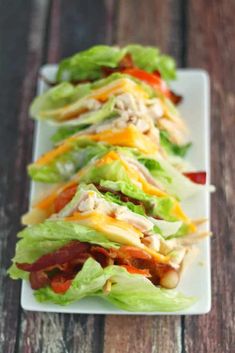 several lettuce wraps with chicken and cheese on them sitting on a white plate