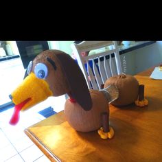 a stuffed dog sitting on top of a wooden table next to a plastic turkey head