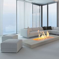 a modern living room with a fire place in the center and large windows overlooking the ocean