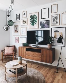 a living room with pictures on the wall and a television in the corner, along with a coffee table