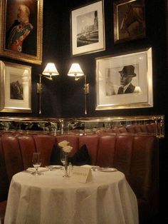 a table with white cloth and two framed pictures on the wall above it in a restaurant