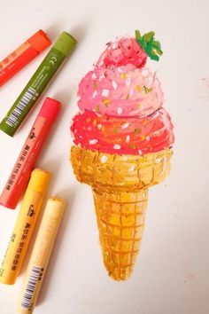 an ice cream cone with sprinkles and crayons next to it