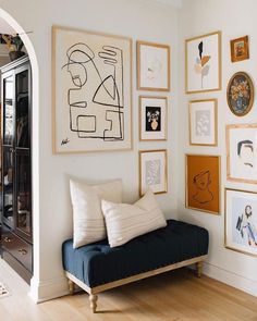 a living room filled with lots of framed pictures on the wall and a black couch