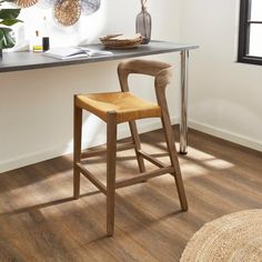 a wooden stool sits in front of a desk with a basket on it and a plant next to it