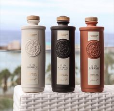 three bottles are sitting on a table near the ocean