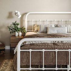 a white metal bed frame with pillows and throw pillows on the headboard in a bedroom