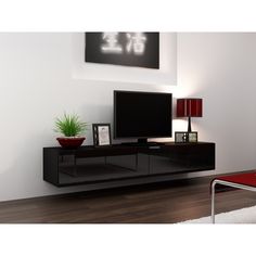 a living room with a large tv on top of a black entertainment center next to a red chair