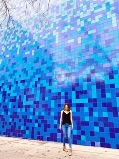 a woman standing in front of a blue tiled wall