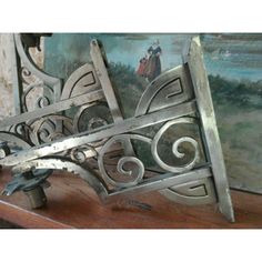 an ornate metal object sitting on top of a wooden table in front of a painting