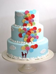 a three tiered cake with balloons on the top is blue and has white icing