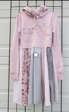 a child's pink hoodie and dress hanging on a wall