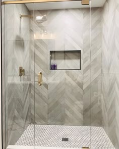 a walk in shower sitting next to a white tiled wall and floor with gold fixtures