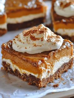 several pieces of dessert sitting on top of a piece of parchment paper with whipped cream