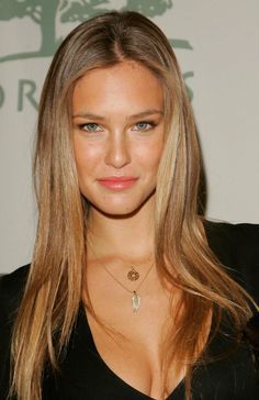 a woman with long blonde hair wearing a black shirt and necklace, posing for the camera