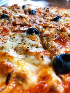 a close up view of a pizza with olives and cheese on it's crust