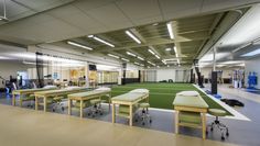 an empty gym with tables, benches and exercise mats on the floor in front of windows