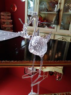 a glass cat figurine sitting on top of a wooden table in front of a china cabinet