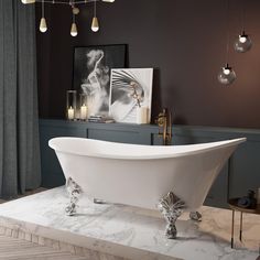 a white bath tub sitting on top of a marble counter next to a painting and candles