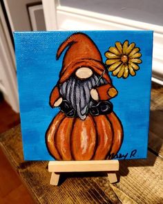 an acrylic painting of a gnome holding a flower on a wooden easel