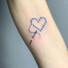 a heart shaped needle tattoo on the arm