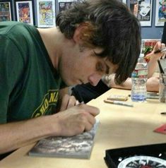 a man sitting at a table writing on a piece of paper