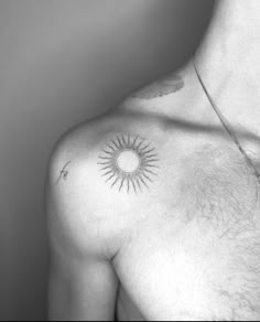 a black and white photo of a man's chest with the sun tattoo on it