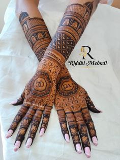 two hands with henna tattoos on them sitting on top of a white tablecloth