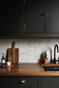 a kitchen with black cabinets and wooden counter tops, including a sink in the center